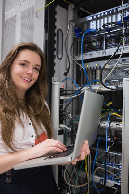 Mujer felizmente usando la computadora portátil para trabajar en servidores