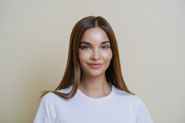 La mujer femenina tierna se ve con admiración y afecto, usa una camiseta blanca, tiene maquillaje, una piel sana