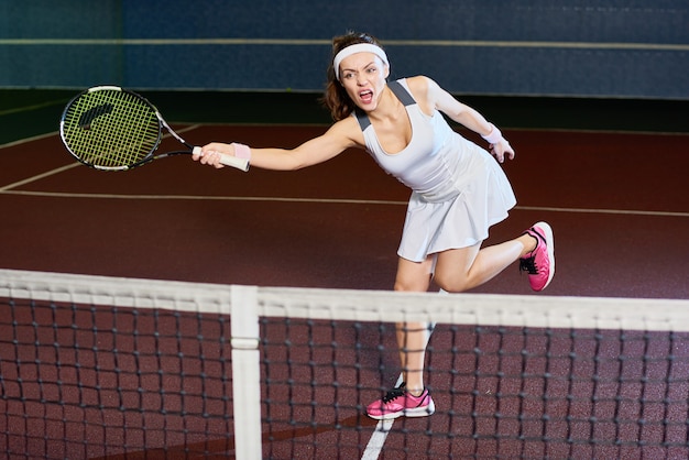 Mujer feroz jugando tenis en la corte