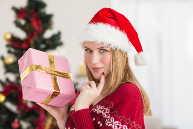 Mujer festiva de pie sosteniendo un regalo rosa