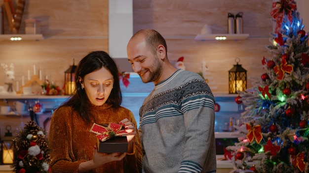 Mujer festiva recibiendo presente del marido celebrando la Navidad