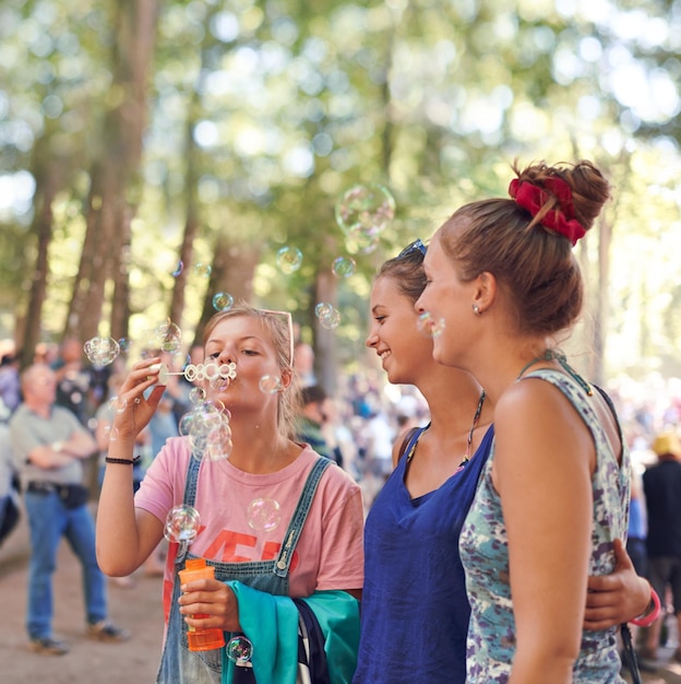 Foto mujer del festival y amigos soplando burbujas al aire libre en un evento o fiesta para celebrar en verano evento de sonrisa y jóvenes felices en la naturaleza o el bosque para entretenimiento de concierto o actuación