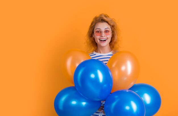 Mujer de fiesta con globo en gafas de sol mujer asombrada sostener globos de fiesta en estudio mujer con globo para fiesta aislado sobre fondo amarillo