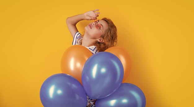 mujer de fiesta con globo en gafas de sol mujer se divierten celebrar globos de fiesta en el estudio mujer con globo para fiesta aislado en fondo amarillo