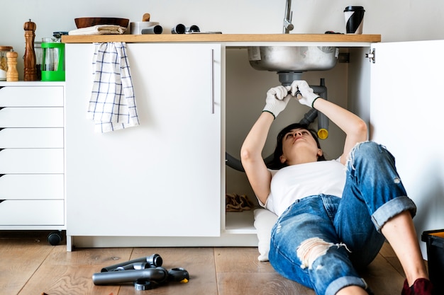 Mujer fijación fregadero de la cocina