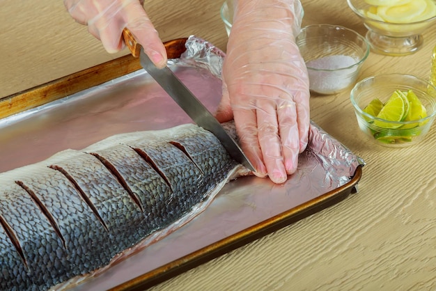 Mujer filete de pescado marinado cocinando pescado crudo en plato de cebolla de cocina en el horno