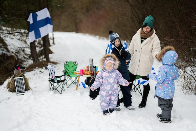 Mujer finlandesa y niños con banderas de Finlandia en un agradable día de invierno Pueblo nórdico escandinavo