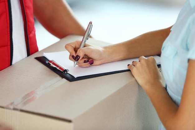 Foto mujer firmando el recibo del paquete de entrega de cerca