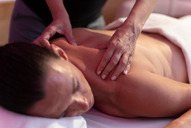 Mujer fisioterapeuta haciendo un masaje a otra mujer en la espalda