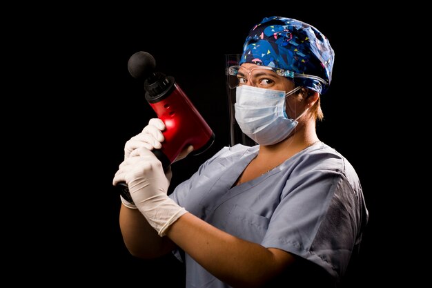 Mujer fisioterapeuta posando con sus herramientas y medicamentos sobre fondo negro mediante protocolo de seguridad anti covid