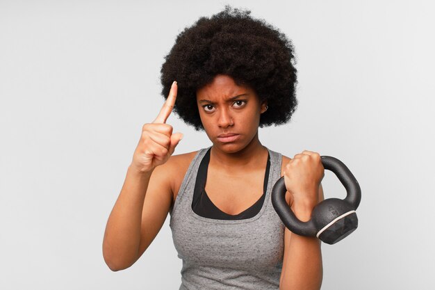 Mujer fitness afro negro con una mancuerna