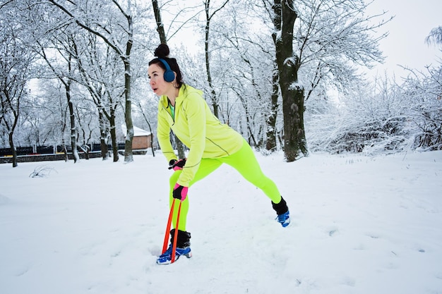 Mujer fitness atlética haciendo ejercicio con banda de resistencia en el fondo del bosque del parque nevado de invierno