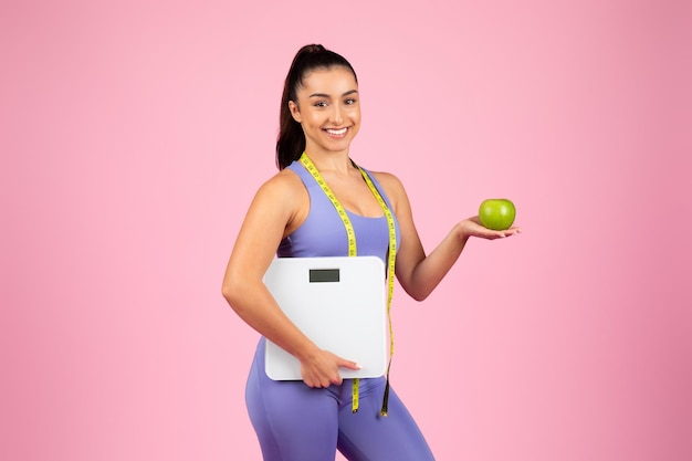 Mujer de fitness con balanza y manzana