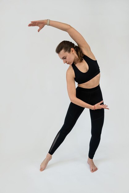 Mujer de fitness caucásica haciendo estiramiento aislada en fondo gris Mujer haciendo ejercicio de fitness