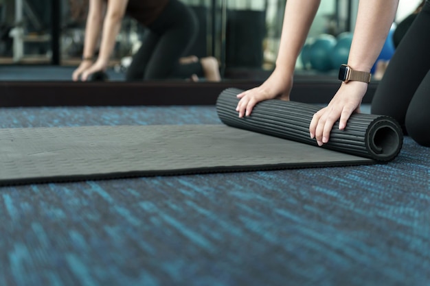 Mujer fitness colchoneta de ejercicio plegable antes de hacer ejercicio en el estudio de yoga colchoneta de yoga rodante después de entrenar un estilo de vida saludable