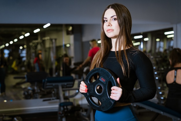 Mujer fitness decidida y fuerte ejercicio con pesos pesados en fitness club deportista sosteniendo ...