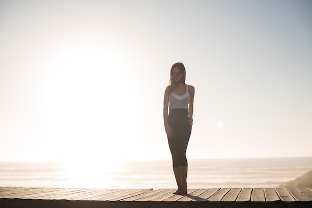 Mujer fitness disfrutando de la hermosa puesta de sol en la playa