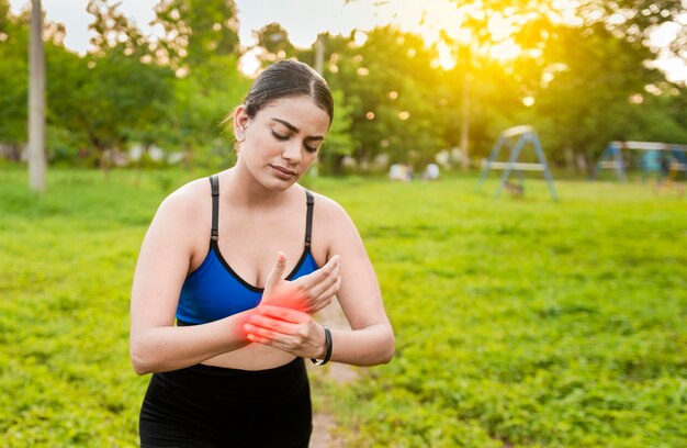 Mujer fitness con dolor de muñeca Concepto de lesión muscular deportiva Chica corredora con dolor de muñeca al aire libre Concepto de dolor de muñeca y artritis en las manos Mujer deportiva con artritis en la muñeca