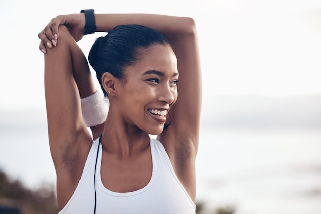 Mujer fitness estirándose y haciendo ejercicio al aire libre en la playa para correr entrenando y pensando en la motivación o la meta durante el entrenamiento Feliz atleta corredora haciendo un calentamiento para cardio en Brasil