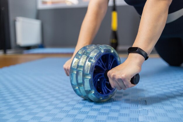 Mujer fitness haciendo ejercicio con rueda de abdominales en la habitación Estilo de vida saludable