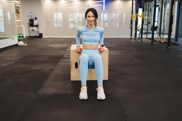 Mujer fitness haciendo ejercicios de tríceps en caja de salto crossfit de madera