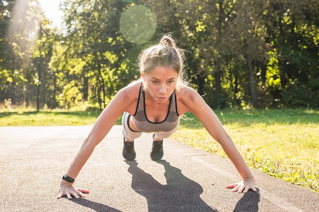 Mujer fitness haciendo flexiones durante el entrenamiento de entrenamiento cruzado al aire libre