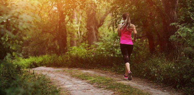 Mujer fitness joven corriendo en la pista forestal de la mañana. Vivir en forma saludable.