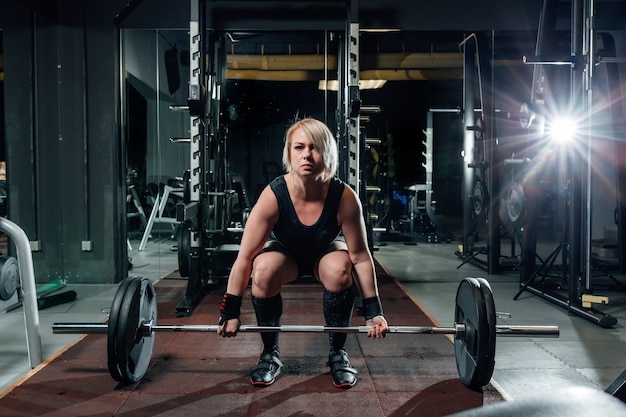 Mujer fitness joven muscular levantando un peso crossfit en el gimnasio.