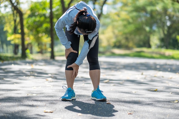 Mujer fitness joven sosteniendo su lesión en las piernas de los deportes, dolor muscular durante el entrenamiento