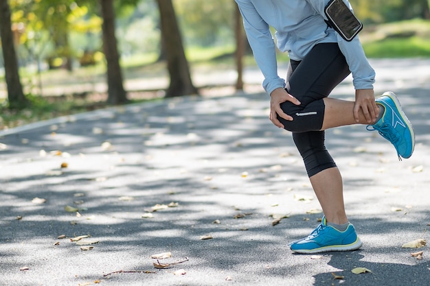Mujer fitness joven sosteniendo su lesión en las piernas de los deportes, dolor muscular durante el entrenamiento