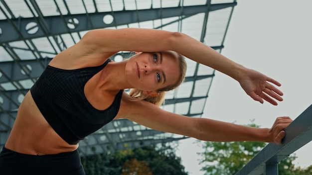 Mujer fitness motivada flaca haciendo deporte en el entrenamiento del estadio ejercicio de estiramiento pose de curva lateral
