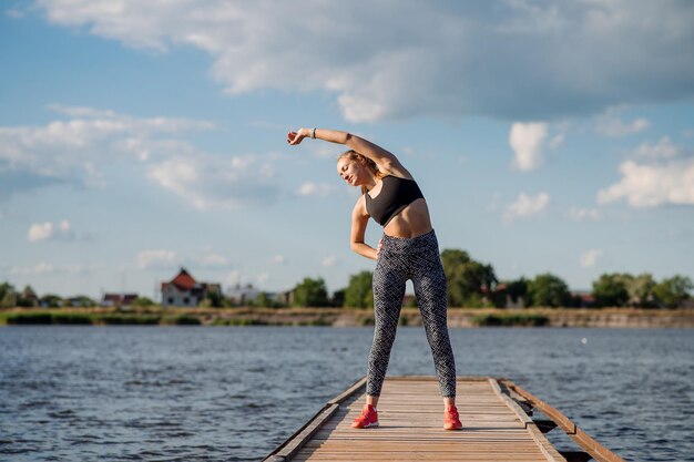 Mujer fitness en ropa deportiva haciendo ejercicios en el muelle