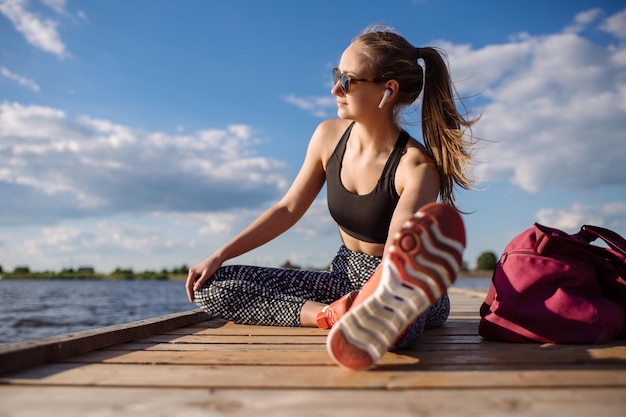 Mujer fitness en ropa deportiva haciendo ejercicios en el muelle