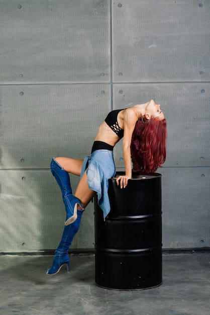 Mujer fitness sobre fondo de hormigón de cemento cerca de un barril negro