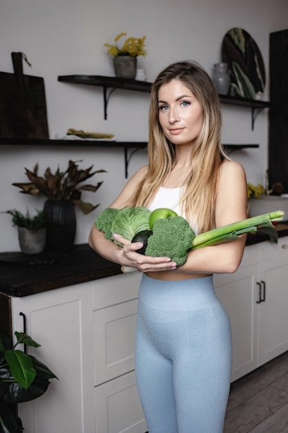 Una mujer fitness tiene un lleno de verduras frescas crudas