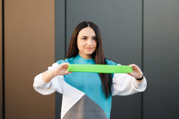 Mujer fitness trabajando con banda de goma de fitness al aire libre Entrenamiento de niña en forma con expansor de goma concepto de estilo de vida saludable