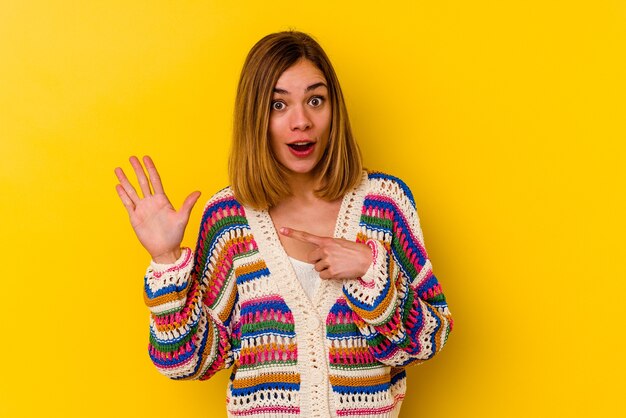 Mujer flaca caucásica joven aislada en amarillo sonriente alegre mostrando el número cinco con los dedos.