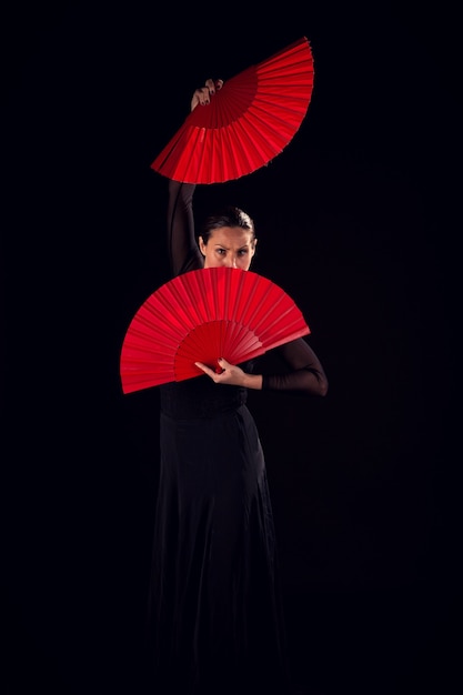 Mujer flamenca con vestido negro y abanico rojo en el rostro