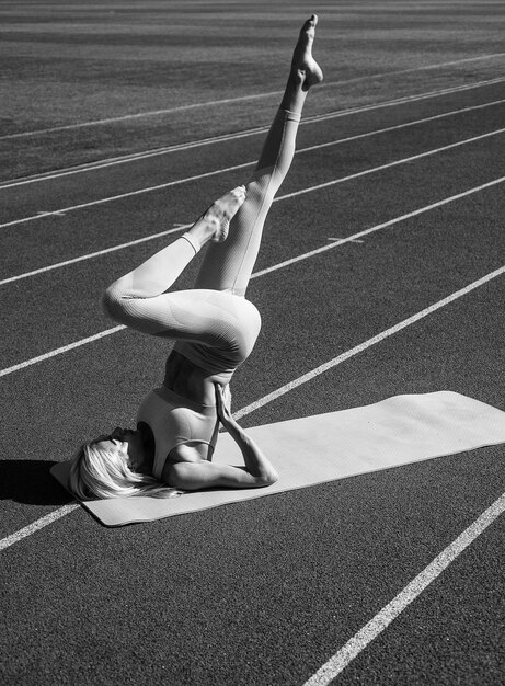 Mujer flexible que se extiende en el estadio de gimnasia deportiva