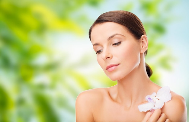Mujer con flor de orquídea sobre fondo verde