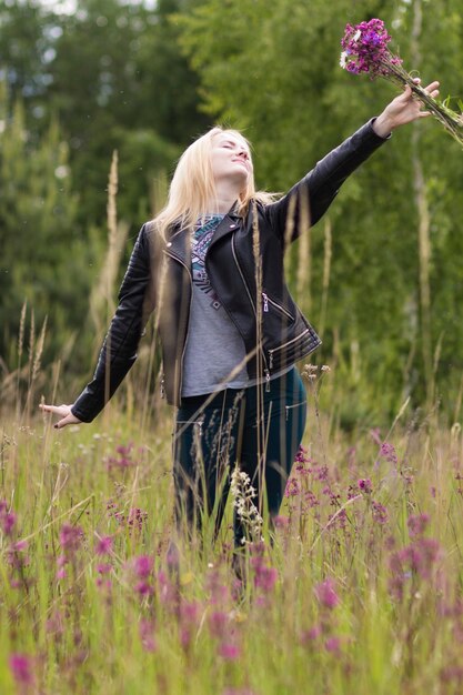 Foto mujer con flores de pie en el campo