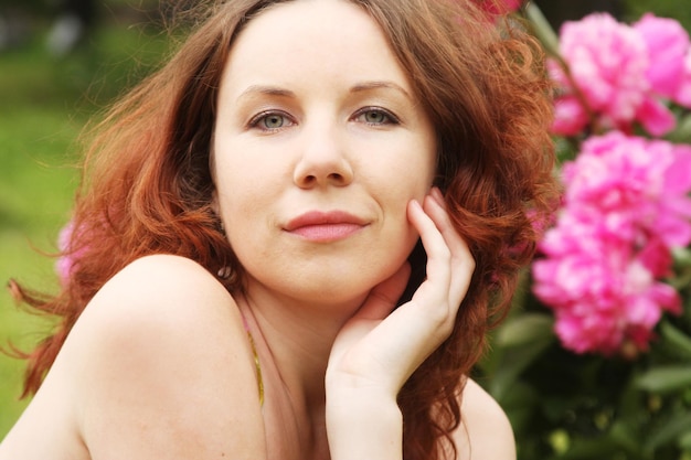 Mujer con flores posando en el parque de verano