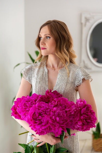 mujer florista creando ramos de flores en el taller El empresario sostiene un ramo de peonías