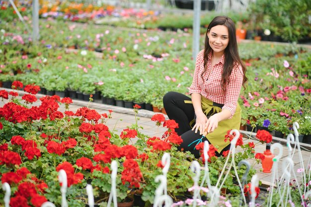 Mujer florista trabajando en su tienda de flores de pie rodeada de plantas