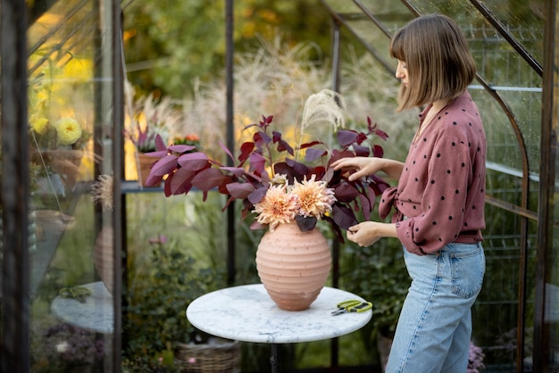 Mujer floristería hace un hermoso ramo en invernadero en el patio trasero