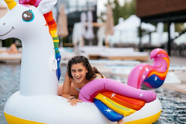 Mujer en flotador inflable de colchón de juguete de unicornio en la piscina