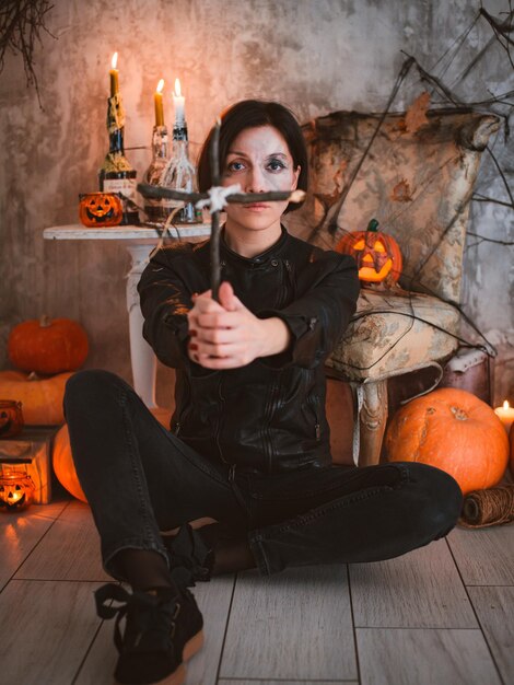 Mujer en el fondo de las decoraciones festivas de Halloween con una cruz de madera