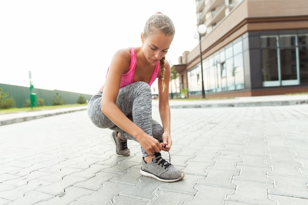 Mujer en forma atando cordones de zapatos al aire libre Estilo de vida activo Correr por la mañana