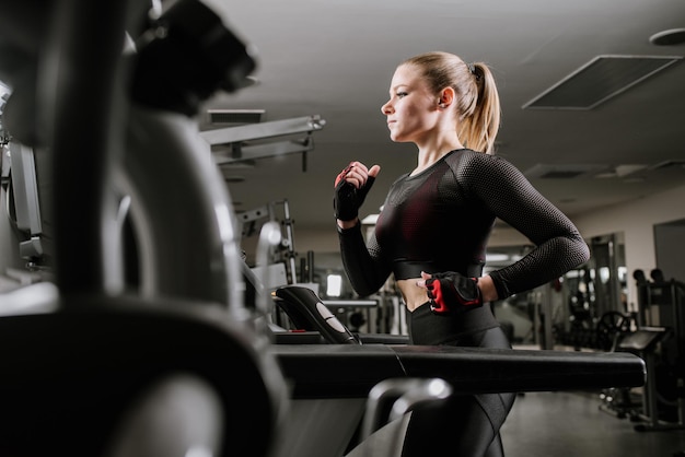 Una mujer en forma corriendo en una caminadora en el gimnasio