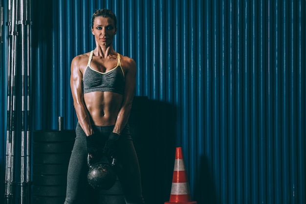 Mujer en forma entrenando levantando pesas rusas en el gimnasio